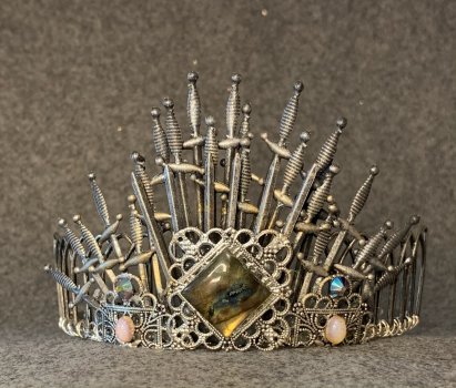Silver tiara made from swords on a gray background
